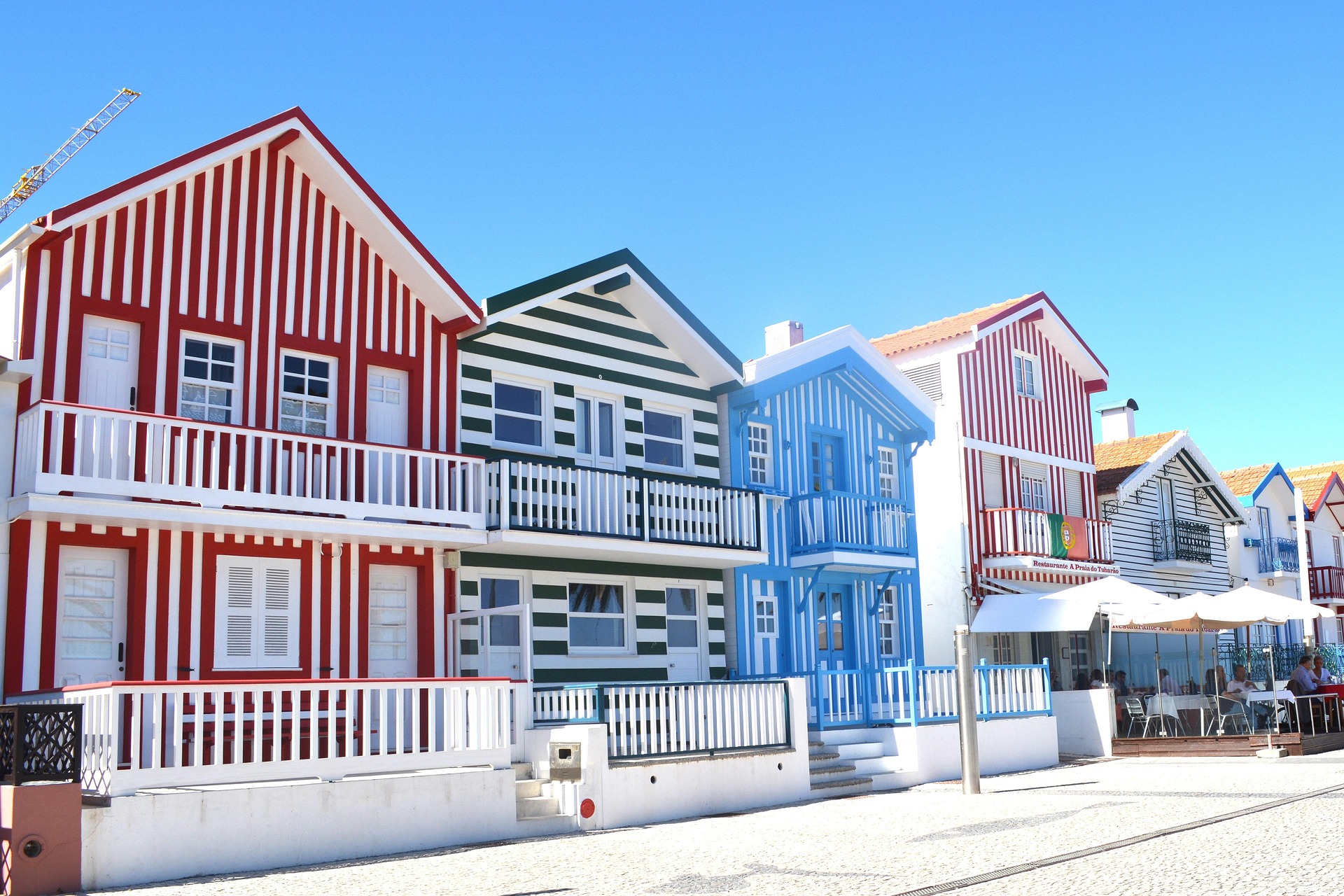 Iconic colorful striped fishermen’s houses of Costa Nova against sand dunes and the Atlantic Ocean
